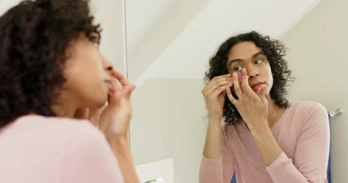 Non-binary person grabbing sponge, dabbing blush before placing gel patch in bathroom for skincare