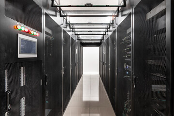 Data center server room with rows of rack cabinets and illuminated aisle corridor