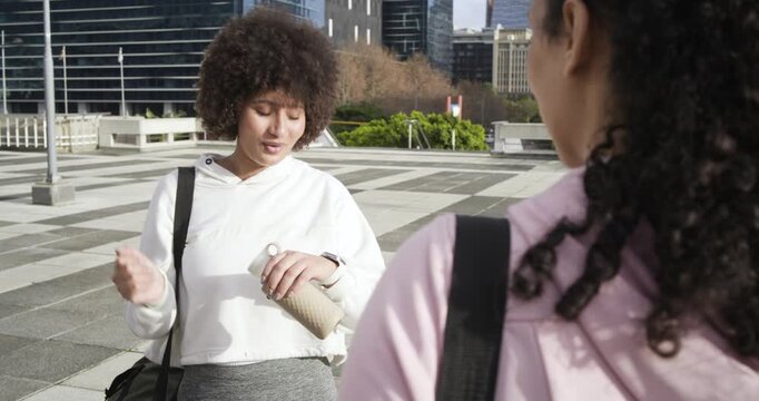 African American friends greeting in plaza twisting cap checking watch reminding friend of plans