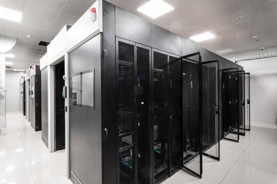 Black server racks arranged in a modern data center room with clean white flooring and overhead lighting