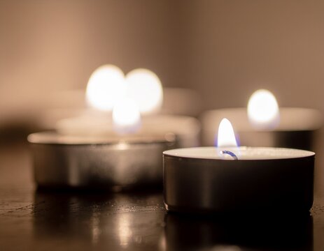 A serene close-up of multiple small tea light candles burning with a warm, soft glow, creating a tranquil and intimate atmosphere, perfect for quiet contemplation and relaxation