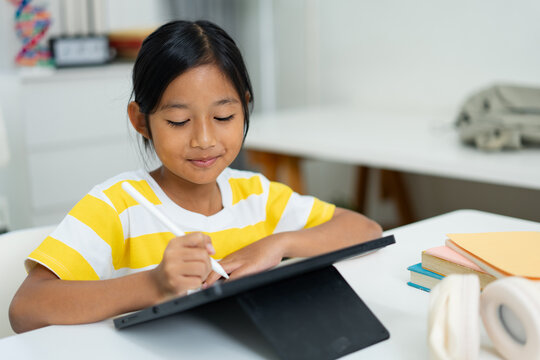 Asian girl writing on digital tablet with stylus pen for online learning
