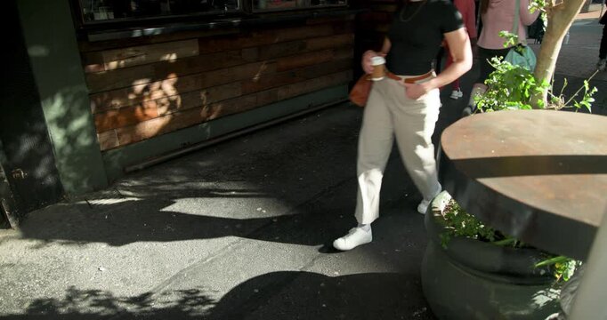 Diverse pedestrians walking outside wooden storefront and planter, window drawing them with coffee