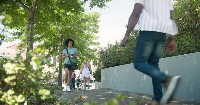 Diverse pedestrians walking uphill to shops on sidewalk, passing and pushing bicycle and stroller