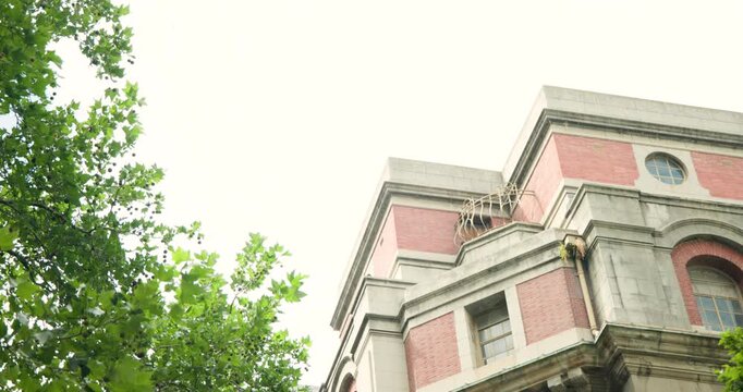 Camera is tilting down after operator input, revealing brick facade with trees to show details