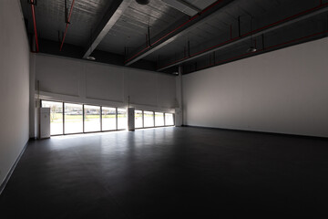 Obraz premium Spacious industrial warehouse interior with large windows allowing natural light to illuminate the empty space