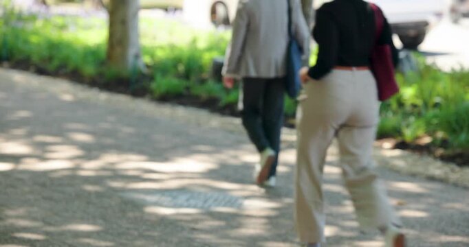 Pedestrians are crossing tree-lined path carrying bags and coffee during morning commute