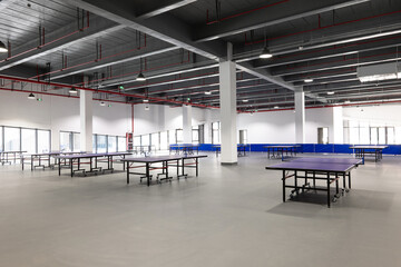 Naklejka premium Indoor table tennis hall with multiple empty tables and modern industrial architecture