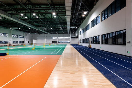 Indoor sports complex featuring badminton courts and running track with modern lighting and flooring