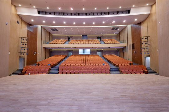 Spacious multi-level auditorium with wooden interior structure and empty seating rows