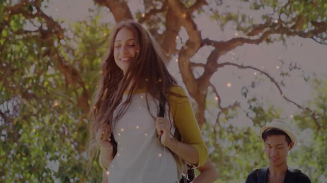 Lead woman fixing straps on park path, camera rising, sparkling particles over group, education