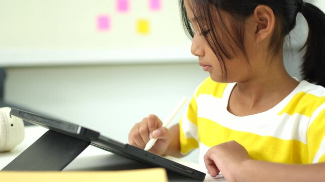Child girl watching online tutorial and drawing digital pictures using digitized pen and digital tablet