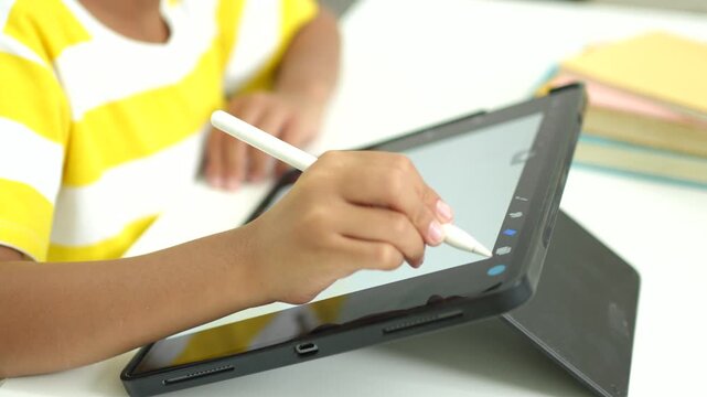 Child girl watching online tutorial and drawing digital pictures using digitized pen and digital tablet