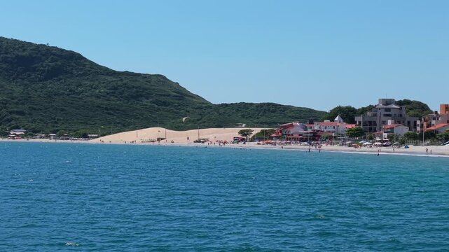 Praia dos Ingleses coastline with ocean water sandy beach dunes and seaside buildings Santa Catarina Brazil, aerial telephoto backdrop