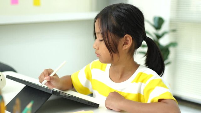 Child girl watching online tutorial and drawing digital pictures using digitized pen and digital tablet