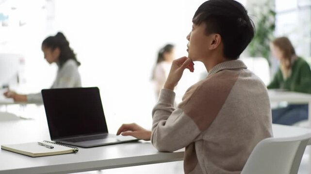 Diverse person, ambiguous gender, focused on laptop in a modern, minimalist learning environment with natural daylight & bokeh, achieves an inspired 'aha!' moment. Personal growth concept