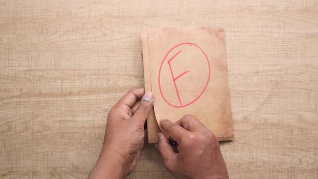 Person holding papers with f grade circled in red, educational failure concept
