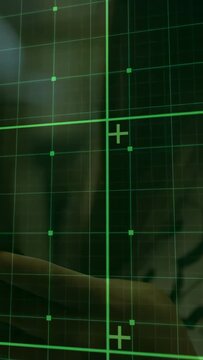 Phone camera capturing HUD output, thermal scope showing green reticle grid for surveillance tech