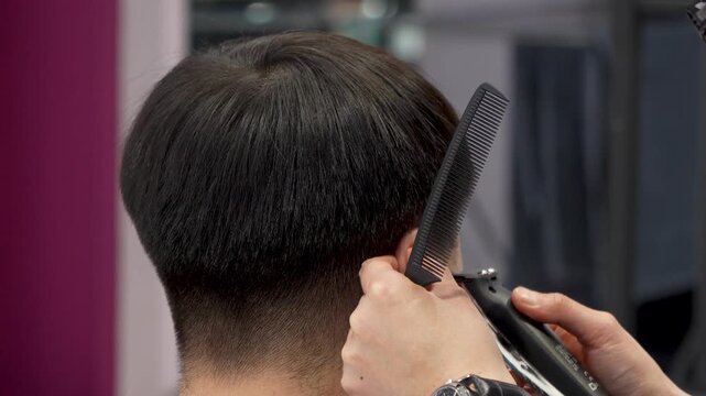 Hairdresser trimming hair with a clipper and a comb