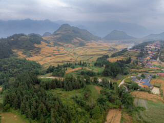 Obraz premium Aerial view of a rural village in Quan Ba, Ha Giang, Vietnam, nestled among mountains and rice terraces. The houses are built in traditional style, blending with nature.