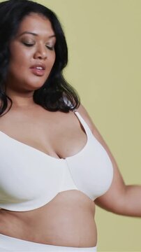 Vertical video: Model reacting to cue, posing to showcase white underwear on pale green backdrop