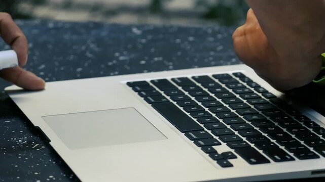 Close up hand wiping laptop keyboard with yellow microfiber cloth for electronics maintenance