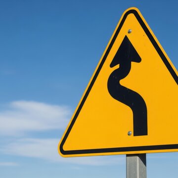 Winding Road Ahead Warning Sign Against Clear Blue Sky