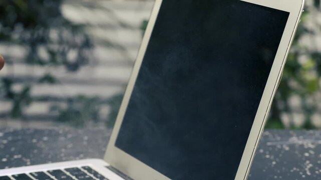 Hand wiping laptop screen with microfiber cloth tech maintenance and workplace hygiene