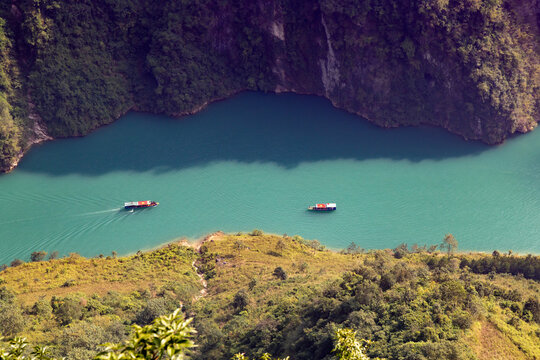 Tourists enjoy a boat ride on the turquoise waters of the Gam River, surrounded by lush green mountains, in Ha Giang province, Vietnam. A scenic adventure.