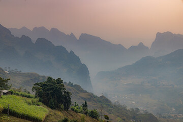 A scenic view of the mountains in Lung Ho, Yen Minh, Ha Giang, Vietnam, showcasing the natural beauty of the region. The landscape features rolling hills and a small village below. © Zenstratus