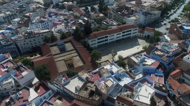 Top view of rooftops revealing Chefchaouen city and mountains in haze