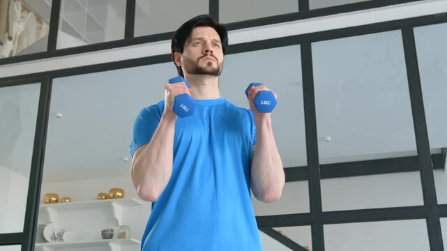 Active sporty fitness man practicing dumbbell hammer curl workout, building strength in arm muscles and boosting athletic performance during sports training at home..