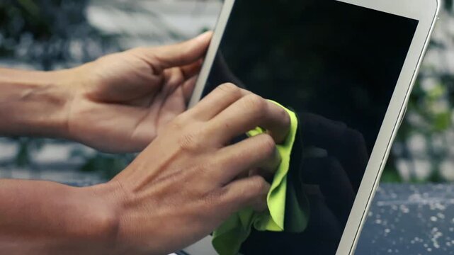 Hand wiping laptop screen with microfiber cloth tech maintenance and workplace hygiene