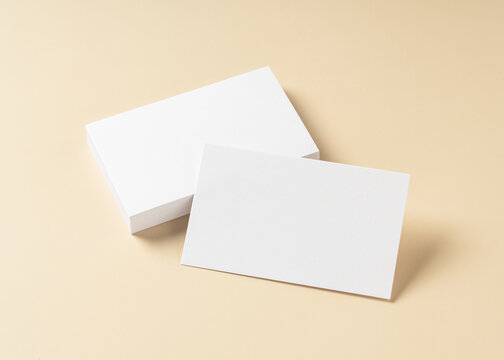 Blank white business cards mockup on beige background with soft shadows