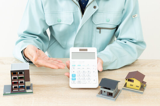 作業着の男性と家模型