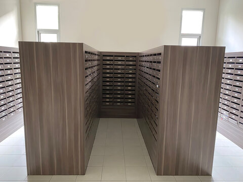 Symmetrical view of apartment mailbox room with wooden mailboxes under bright lighting.