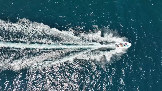 Aerial drone top down tracking video of small inflatable rib speed boat cruising in mediterranean sea