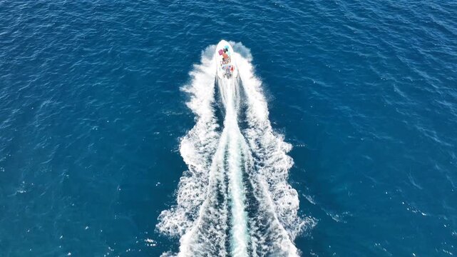 Aerial drone top down tracking video of small inflatable rib speed boat cruising in mediterranean sea
