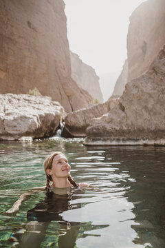 Young woman marvels at scenery while swimming in Wadi in Oman