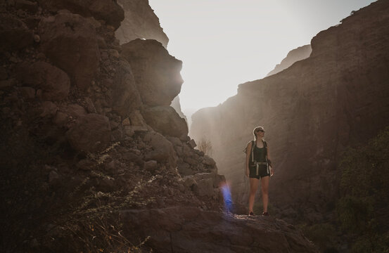 Woman hikes through beautiful canyon in Oman at golden hour