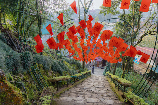 A stone path is decorated with red communist flags in Ham Rong Park, Sa Pa, Lao Cai, Vietnam. The flags create a festive atmosphere for tourists visiting the area.