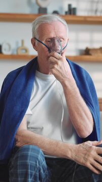 Modern technology in medicine, old man using oxygen machine with nebulizer. Senior sick male person inhaling concentrated oxygen from nebulizer, recovery breathing and relive hypoxia after pneumonia