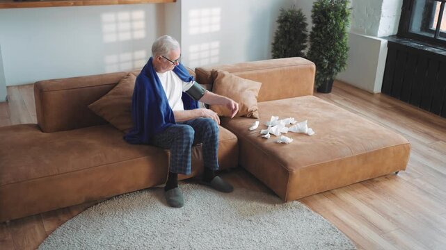 Healthcare and medicine in old age, senior man taking blood pressure at home. Modern technology for stay healthy and controlling body condition, aged male person suffering by hypertension and cold