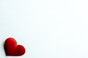 Fototapeta premium Red heart-shaped decorations arranged on a clean white background, placed in the bottom-left corner, leaving ample blank space for text or other elements. Used for Valentine's Day