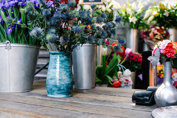 Naklejka premium Cozy and authentic rustic flower shop counter with dried lavender and vintage gardening tools. An intimate workshop scene showing a hand tying a flower bouquet on a weathered wooden table with antique