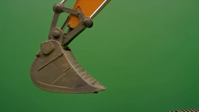 Hydraulic excavator bucket moving against green background.