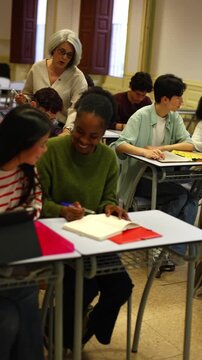 Senior teacher guiding diverse high school students during lesson