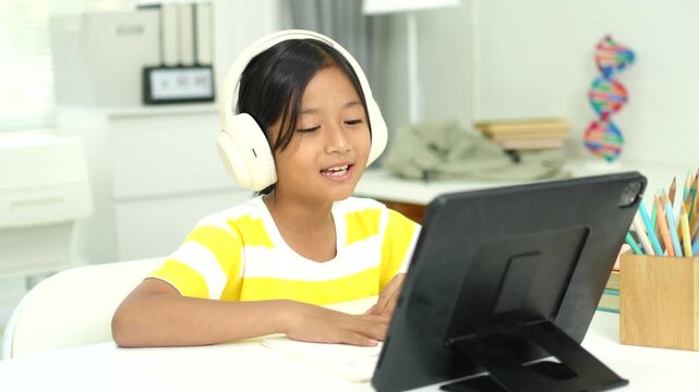 Asian girl with headphones enjoying online class on digital tablet