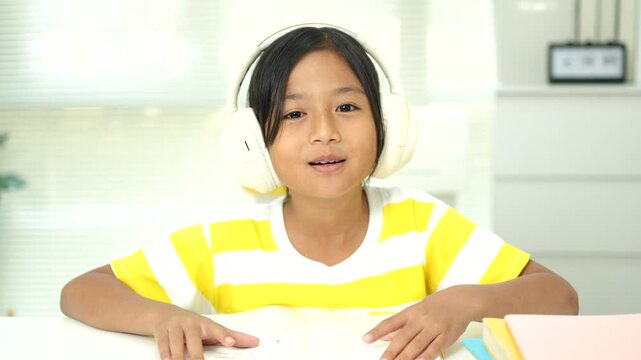 Asian girl with headphones enjoying online class on digital tablet