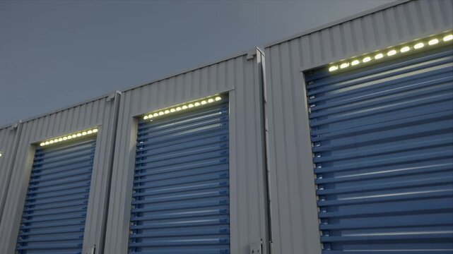 Row of illuminated self storage unit doors at dusk.